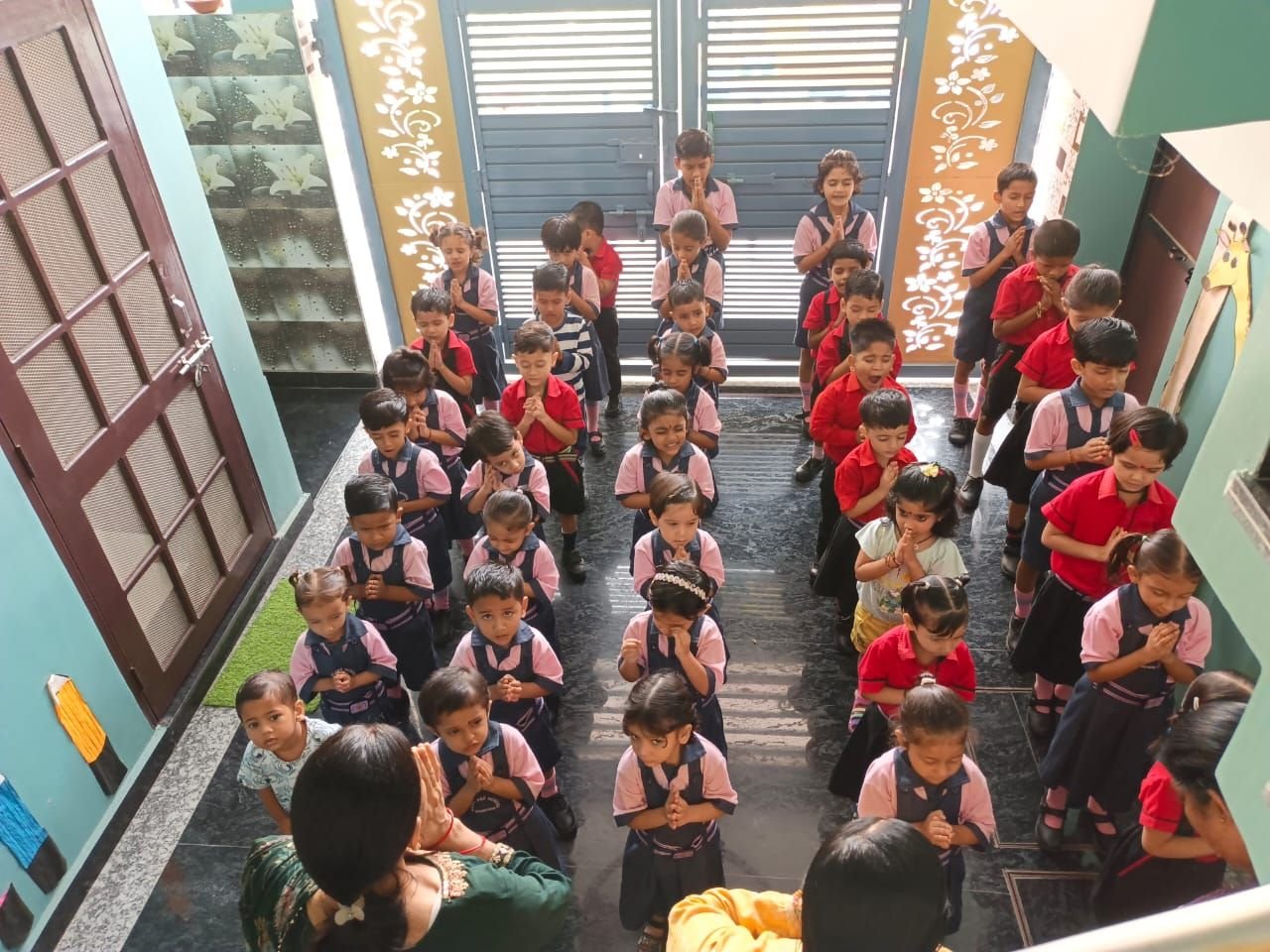 Children standing in rows with folded hands during morning prayer